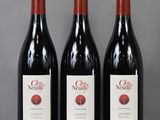 three bottles of red wine are lined up on a table