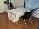a white desk with two black chairs in a room