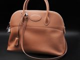 a brown leather handbag on a black background