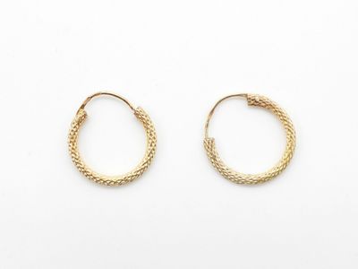 une paire de boucles d'oreilles en or sur fond blanc