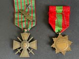 two medals and a cross on a table with a red and green ribbon