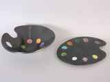 deux assiettes contenant de la peinture et une palette, posées sur une surface blanche