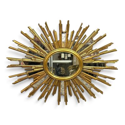 an image of a gold sunburst mirror hanging on a wall