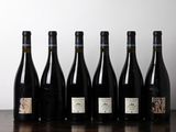 bottles of wine lined up on a table in front of a white wall