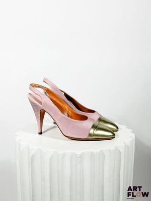 des chaussures à talons hauts roses et dorées posées sur un socle blanc