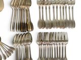 many forks and spoons laid out on a white surface
