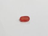 a close up of a red stone on a white surface
