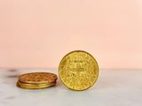 two gold coins sitting next to each other on a marble surface