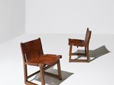 two wooden chairs in a white room with a white wall