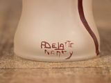 a white vase with a red handle sitting on a table