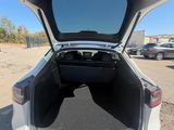 the back of a white car with its trunk open in a parking lot