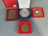 trois médailles d'or et une médaille d'argent dans une boîte rouge