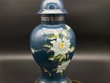 un vase bleu décoré de fleurs, posé sur une table