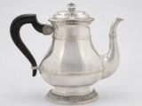 an antique silver teapot with a black handle on a white background