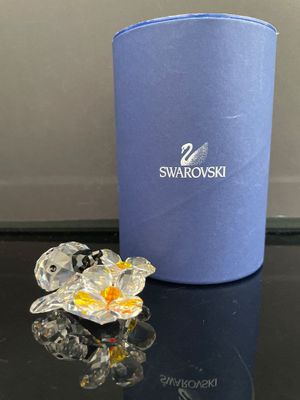 une petite fleur en verre posée sur une table, à côté d'une boîte bleue