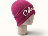 purple wool hat with the word ooh on it on a mannequin head