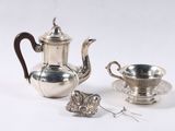 a silver tea pot and a silver cup on a table