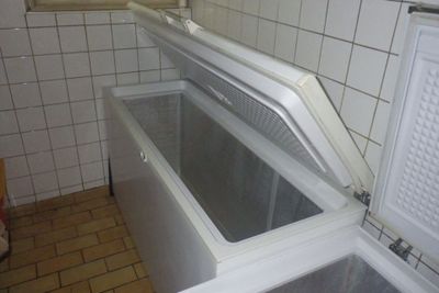 un réfrigérateur ouvert dans une petite pièce aux murs carrelés