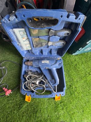 une boîte à outils bleue contenant des outils, posée sur l'herbe