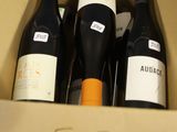 trois bouteilles de vin dans un carton sur une table