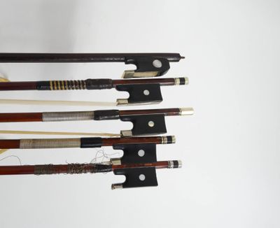 Quatre types différents d'archets de violon sont alignés sur un fond blanc