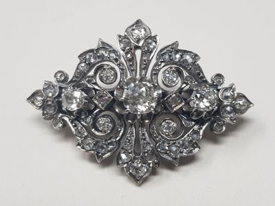 un gros plan d'une broche en diamant posée sur une surface blanche
