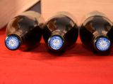 four bottles of wine are lined up on a red cloth