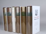 four books in a row on a white surface with a box