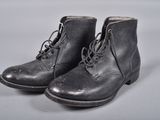 une paire de bottes en cuir noir à lacets posées sur une surface blanche