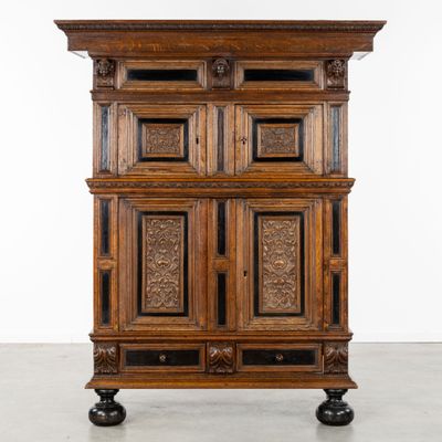 une vieille armoire en bois avec des portes sculptées et des tiroirs montés sur roulettes