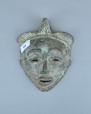 un gros plan d'un masque en métal sur lequel est accrochée une étiquette