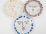 trois assiettes sur lesquelles sont peints des visages, sur un fond blanc