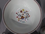 a white bowl with a floral design on it next to cups and saucers