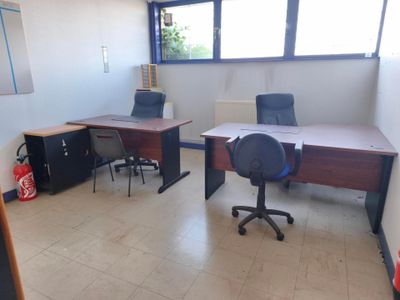 une pièce dans laquelle se trouvent deux bureaux et une chaise