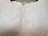 a white shirt with polka dots on it hanging on a hanger