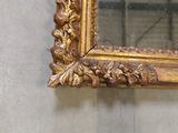 a gold framed mirror hanging on a wall in a room