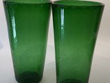 two green glass cups sitting on a white surface