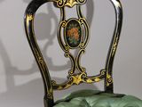 a black and gold chair with a green cushion on it