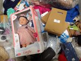 a box with a doll in it sitting on a pile of other toys