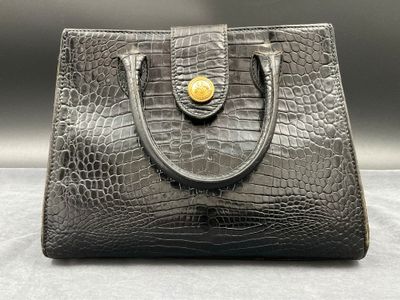an image of a black handbag with a gold button on it