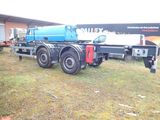 a truck that is parked in the grass with a trailer behind it