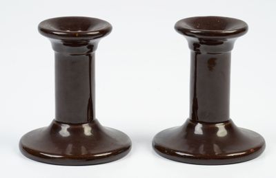 deux bougeoirs marron posés sur une surface blanche