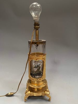 an old fashioned lamp with a picture of a man and woman in a glass bottle