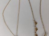 two gold necklaces on a white surface