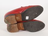 pair of red leather shoes with brown soles on a white surface
