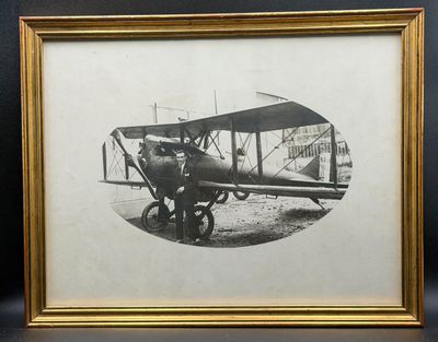 une vieille photo d'un homme debout à côté d'un petit avion