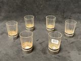 six verres de whisky posés les uns à côté des autres sur une table