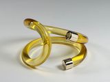 two yellow rings with a silver clasp on a white surface