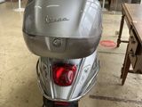 un scooter argenté garé dans une pièce où se trouvent une table et des chaises