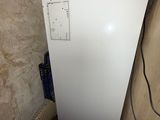 un réfrigérateur blanc dans un coin de la pièce, près d'un mur